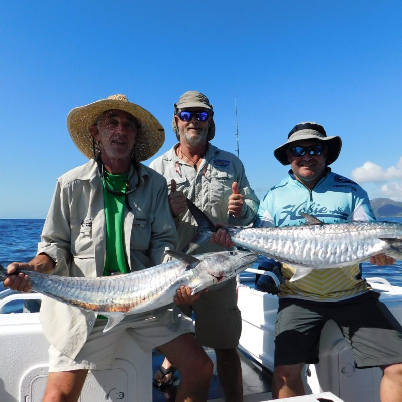 men posing for the camera holding up the fish they caught with airlie beach fishing charters in airlie beach, queensland