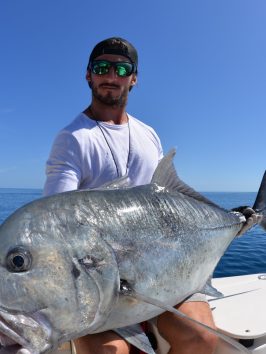 a man posing for the camera holding up the fish he caught with airlie beach fishing charters in airlie beach, queensland