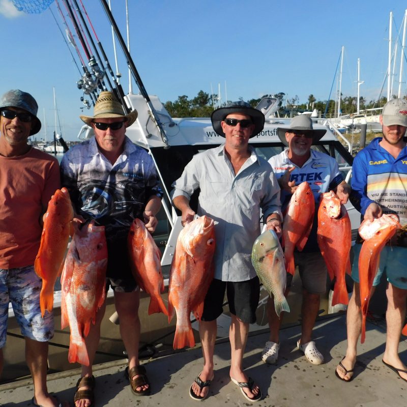 a group of men posing for the camera holding up the fishes they caught with airlie beach fishing charters in airlie beach, queensland
