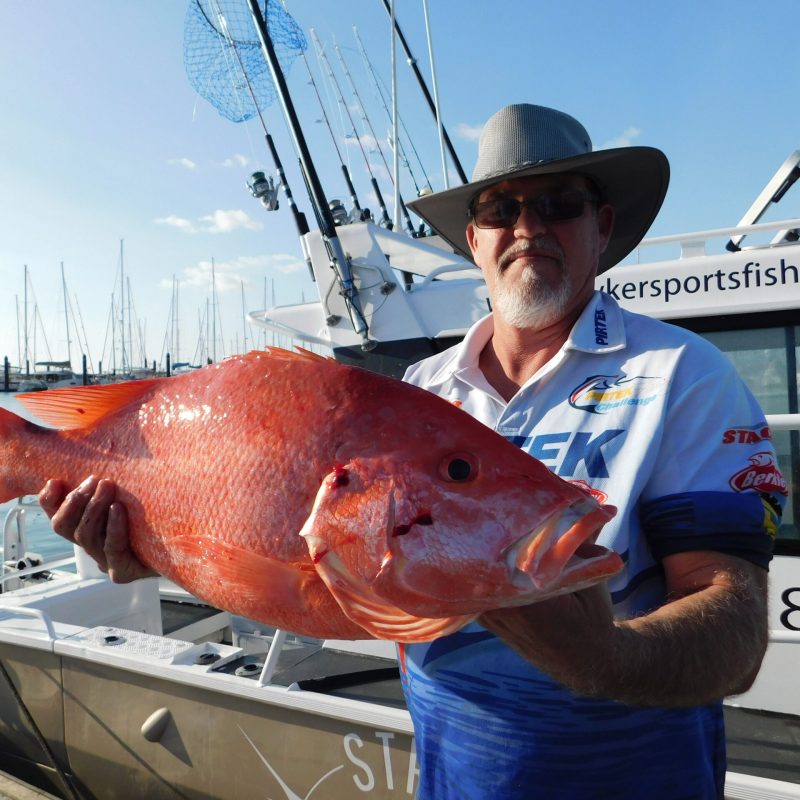 a man posing for the camera holding up the fish he caught with airlie beach fishing charters in airlie beach, queensland