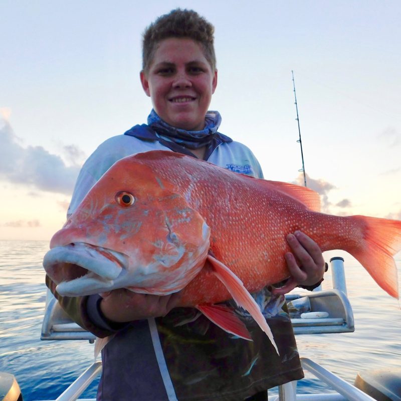 a man posing for the camera holding up the fish he caught with airlie beach fishing charters in airlie beach, queensland
