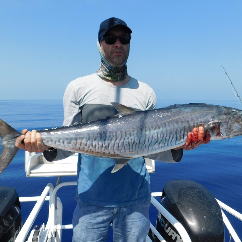 a man posing for the camera holding up the fish he caught with airlie beach fishing charters in airlie beach, queensland
