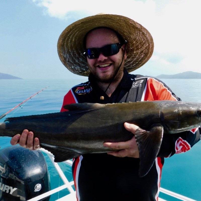 a man posing for the camera holding up the fish he caught with airlie beach fishing charters in airlie beach, queensland