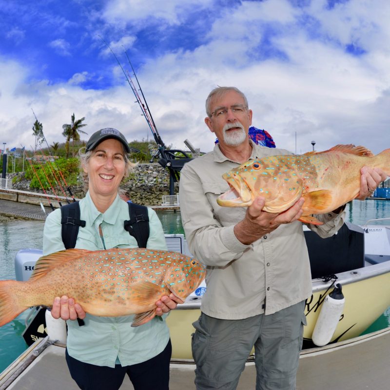 older couple posing for the camera holding up the fish they caught with airlie beach fishing charters in airlie beach, queensland
