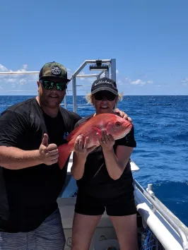 couple posing for the camera holding up the fish they caught with airlie beach fishing charters in airlie beach, queensland